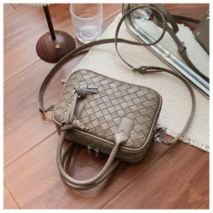 Woven leather handbag detail showing intricate grid pattern, khaki crossbody bag view.