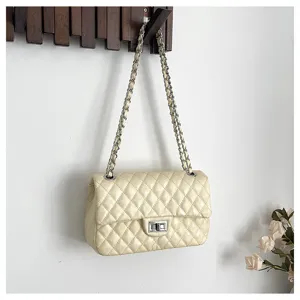 Detailed view of beige quilted chain shoulder bag, classic flap design and metallic strap.