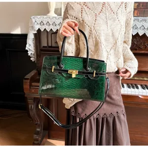 Detailansicht der dunkelgrünen Schlangenhaut-Handtasche mit Goldschloss und Schultergurt.