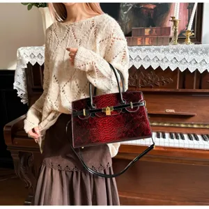 Detailaufnahme einer eleganten roten Schlangenleder-Handtasche mit Schloss und Griffen.
