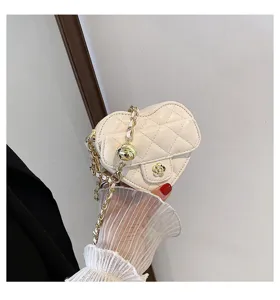 Detailopname van de witte gewatteerde hartschoudertas met gouden ketting en chique sluiting.