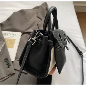 Detailed view of women canvas and leather patchwork handbag with chic top handle and shoulder strap.