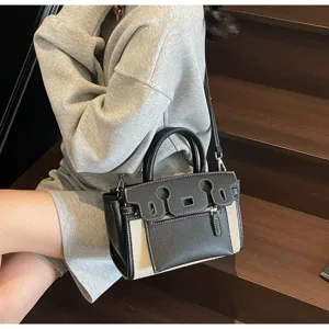 Detail view of a stylish two-tone patchwork shoulder bag with top handle on stairs.