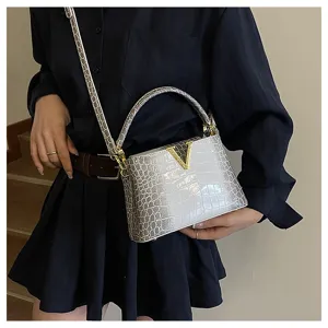Detail view of women's gradient grey crocodile pattern handbag with gold V hardware.
