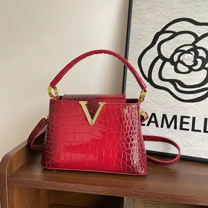 Stylish red crocodile pattern top handle handbag featuring metallic V buckle and strap.