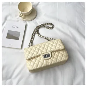 Detailed view of off-white quilted shoulder bag with chain strap and twist lock on fabric.