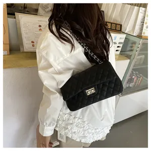 Detailed view of the black quilted chain shoulder bag, showcasing the metallic turn-lock and strap.