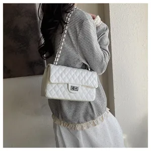 Detail shot of white quilted shoulder bag with metal chain strap worn by model, showing style.