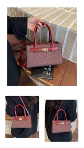 Detailed view of women's retro pattern handbag with contrast red handle and metal lock closure.