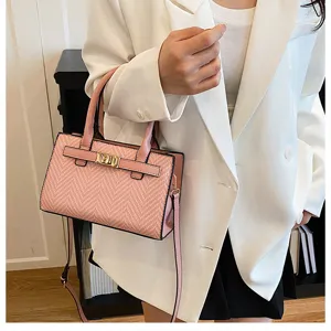 Close-up of pink textured crossbody bag with metal lock detail, worn by model, chic style.