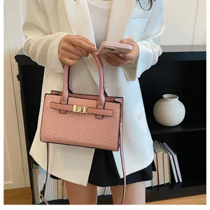 Pink textured shoulder bag with top handle, elegant gold-tone turn-lock design for women.