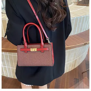 Details of the stylish contrast color houndstooth handbag with gold lock clasp and strap.