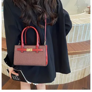 Detail view of stylish contrast tweed crossbody handbag with red leather trim and gold clasp.