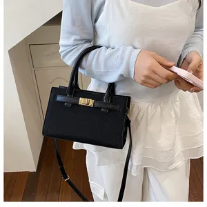 Detailed view of a black structured crossbody handbag with stylish metal lock closure and top handle.