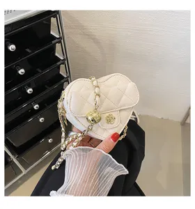 Mini witte hartvormige gewatteerde schoudertas met gouden ketting en stijlvolle bedel.