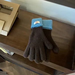 Closeup of women's color-block knit gloves in brown and blue with ribbed cuffs and tag.