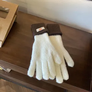Close-up of women's color-block knit five-finger gloves, white with brown cuffs, warm.
