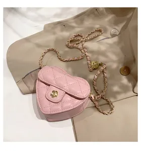 Detailopname van de roze gewatteerde hartschoudertas met gouden ketting en bloemsluiting.