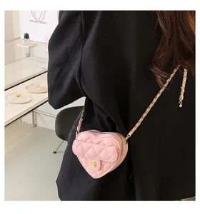 Gedetailleerd uitzicht op een charmante roze gewatteerde hartschoudertas met ketting door model.
