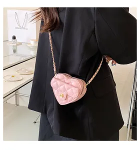 Detailopname van een chique roze gewatteerde hartvormige schoudertas met gouden ketting.
