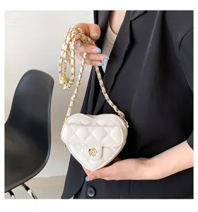 Gedetailleerd overzicht van een mini witte gewatteerde hartvormige tas met ketting.