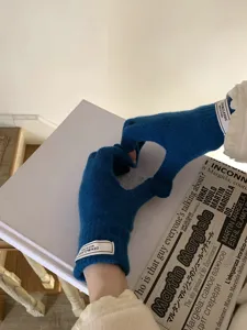 Vista detallada de guantes de punto azul táctiles con un bonito gesto de mano de corazón