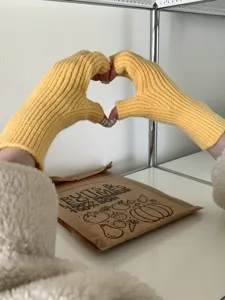 Primer plano de guantes de punto sin dedos amarillos textura suave para calidez diaria.