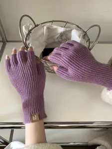 Primer plano detallado de cómodos guantes morados de punto acanalado con etiqueta en la muñeca.