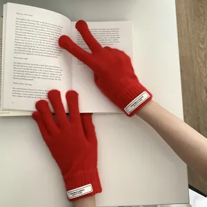 Primer plano detallado de guantes táctiles de punto rojo vivo con elegante parche de letras.