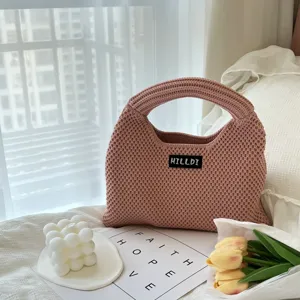 Detailansicht der niedlichen rosa Strickhandtasche mit gemütlichem Schlafzimmerhintergrund.