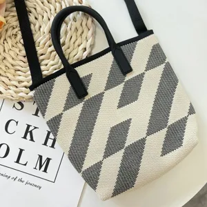 Detailansicht einer schwarz-weißen Strick-Tragetasche mit geometrischem Muster und stabilen Griffen.