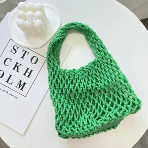 Primo piano della borsa a rete verde, dettaglio della borsa in corda di cotone su tavolo bianco.