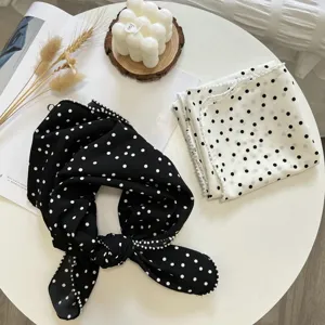 Gros plan détail du foulard carré à pois noir et blanc avec bordure perlée délicate.