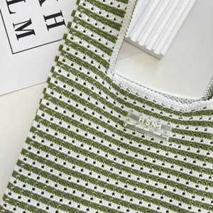 Gros plan sur les details du sac cabas en tricot ajoure vert et blanc, belle texture.