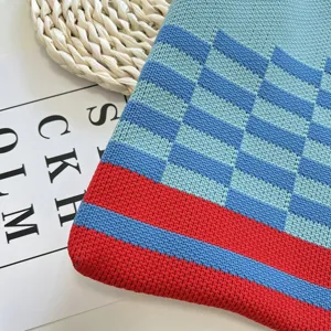 Gros plan détail sac en tricot avec motif colorblock vibrant en bleu, bleu clair et rouge.