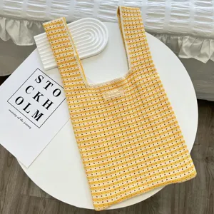 Vue detaillee du sac cabas en tricot ajoure a rayures jaunes et blanches sur une table.