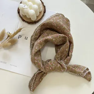 Vue de détail du foulard carré en coton et lin à bordure de perles au motif floral estival.
