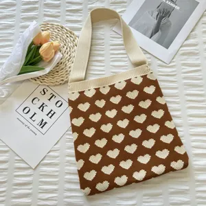 Détail de sac bandoulière tricoté marron avec motif cœur blanc et accessoires esthétiques.
