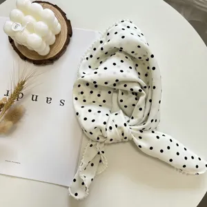 Vue rapprochée détaillée d'un foulard élégant à pois blancs avec bordure de perles.