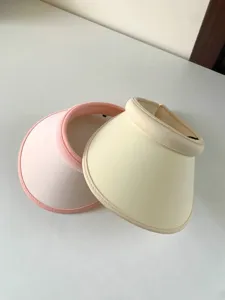 Gedetailleerde close-up van modieuze stijlvolle open zonnekleppen in roze en beige kleuren.