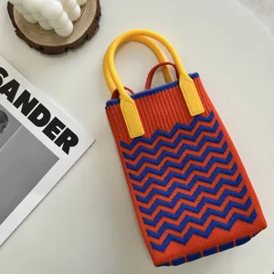 Vue détaillée du mini sac tricoté avec un motif zigzag orange et bleu et une poignée jaune.