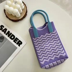 Gros plan sur le mini sac de téléphone en tricot violet à motif de vagues et poignées bleues.