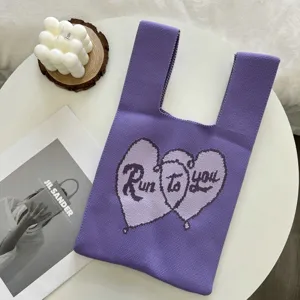Détail de sac cabas en tricot violet avec jacquard cœur et motif texte contrasté.
