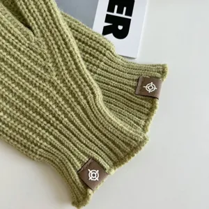 Detailopname van groen gebreide winterhandschoenen zonder vingers met een label.