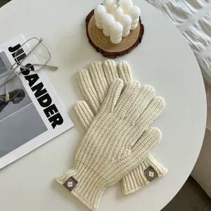 Detailopname van gezellige ecru gebreide handschoenen met geribde boorden voor de winter.