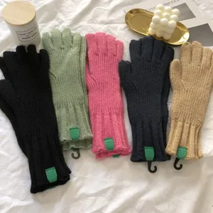 Detail view of solid color knitted winter gloves in multiple colors with cute green tags.