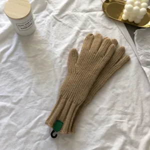 Close-up shot of winter warm knitted gloves in solid camel color on a cozy white fabric.