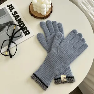 Vista detallada de guantes táctiles de punto azul grisáceo en una mesa blanca minimalista.