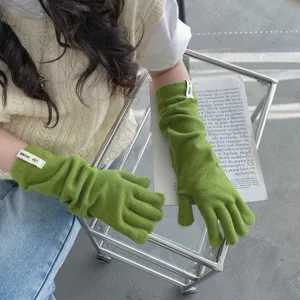 Detailaufnahme von langen grünen Strickhandschuhen mit Fingern, einfarbiger Winterwärmer.
