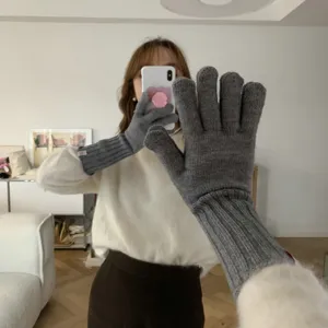 Detail shot of gray knitted gloves featuring long ribbed cuffs and split fingers, cozy winter wear.